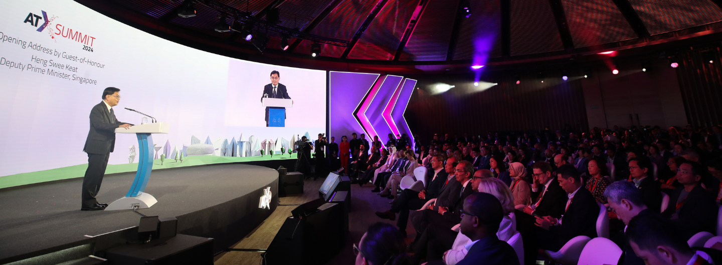 ATx Summit 2024: Speaker at podium before audience, screen shows speaker also.
